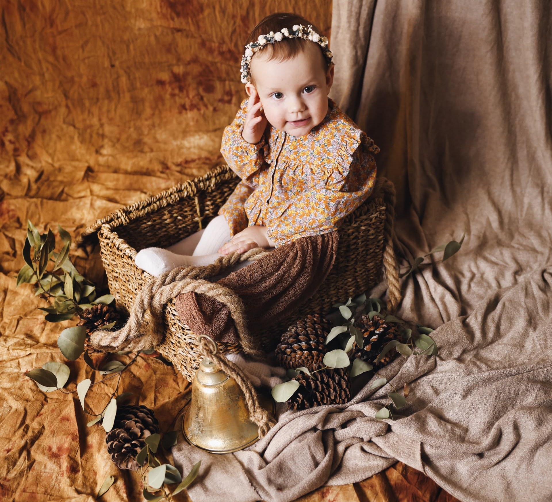 Toddler girl with a flower crown sitting in a woven basket
