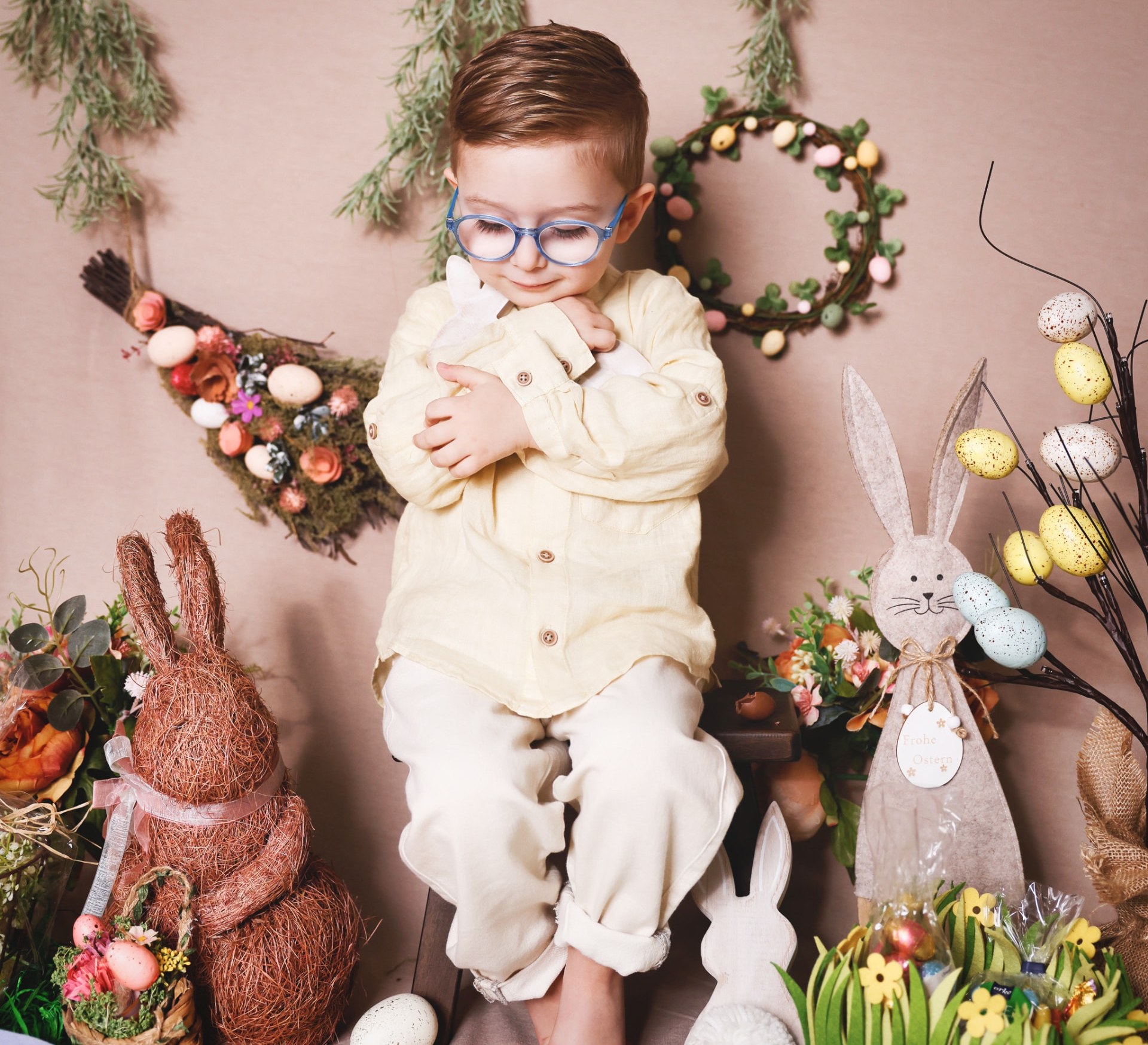 Young boy in a linen shirt hugging a bunny toy