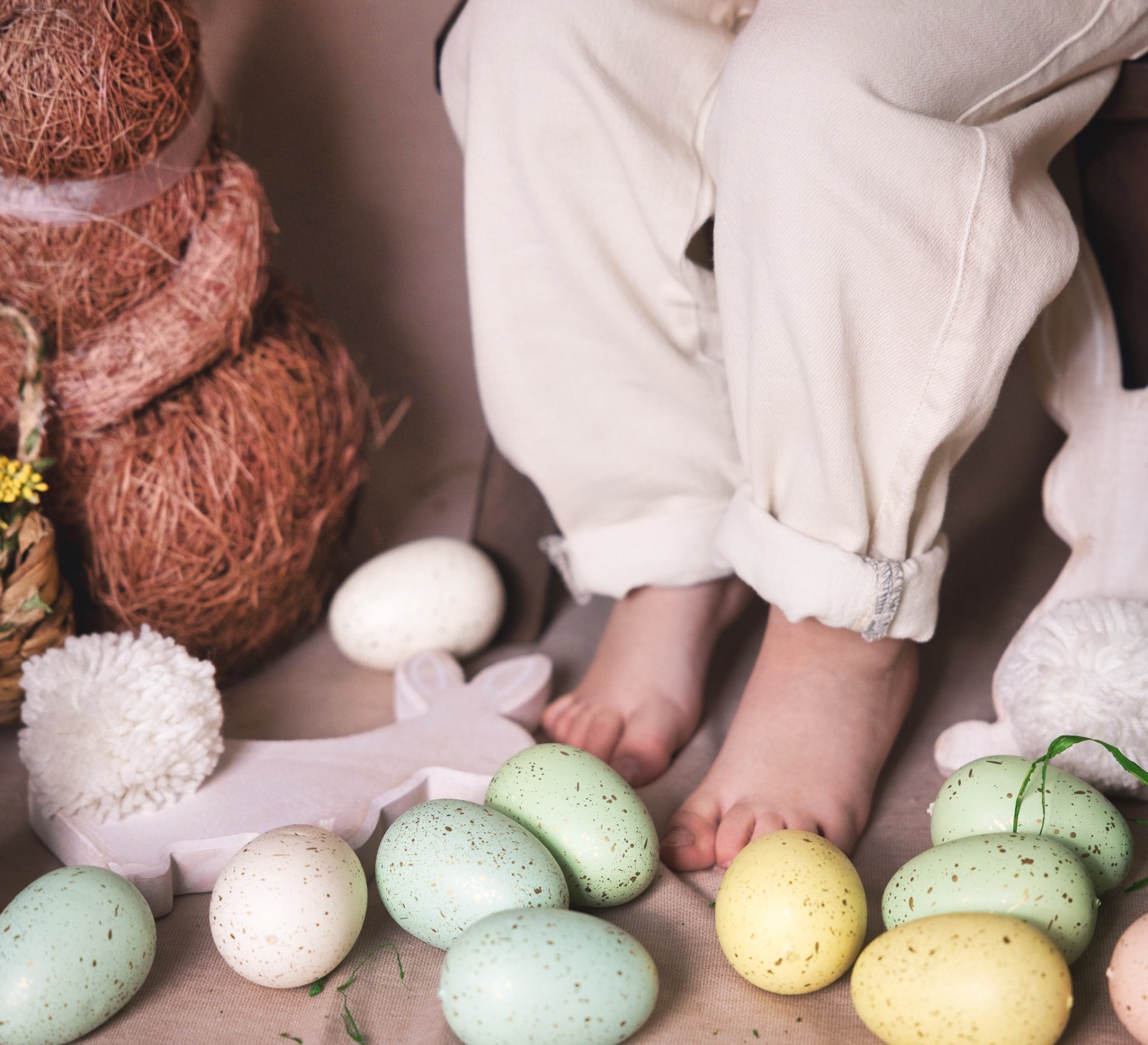 Bare baby feet among pastel speckled eggs on linen