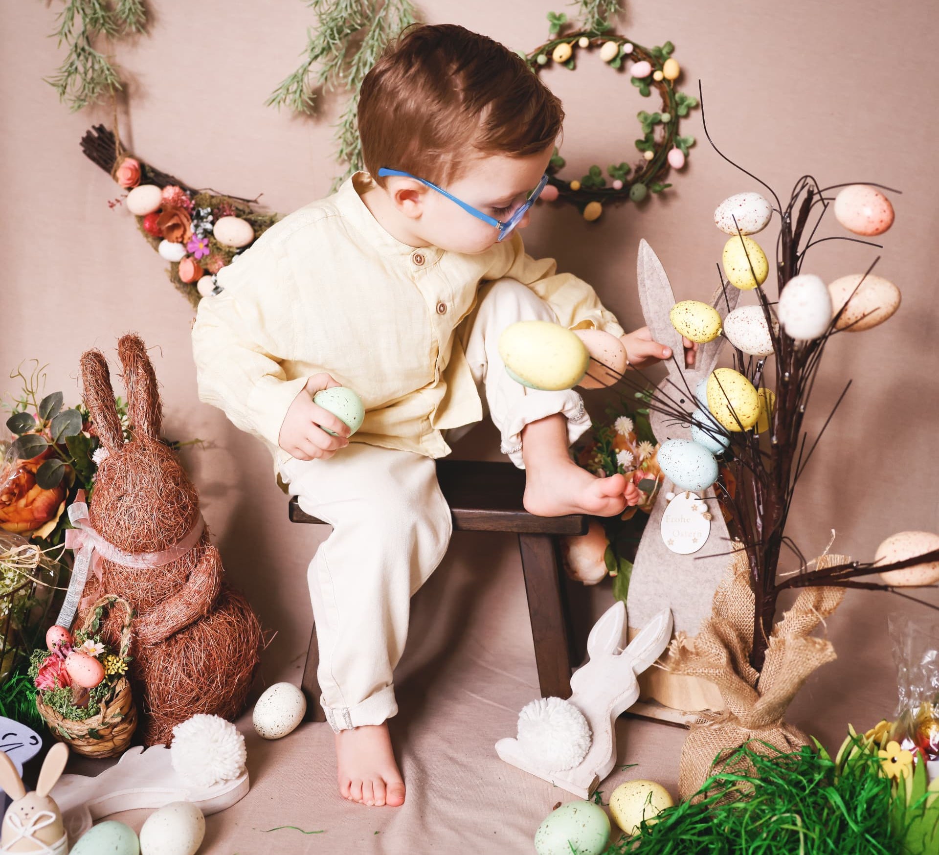 Boy reaching for painted eggs on a decorated branch