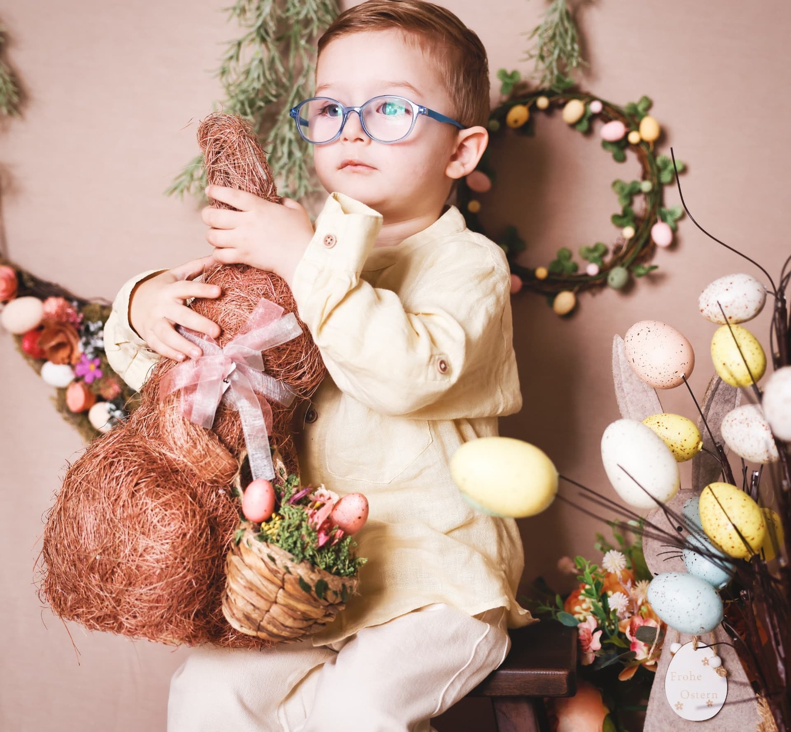 Boy in glasses holding a woven bunny in a spring set