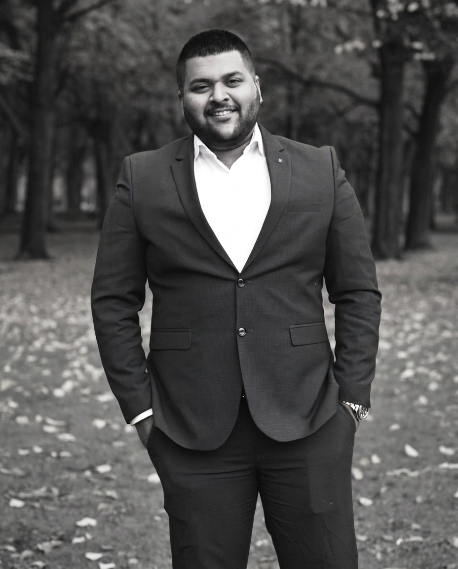 Man in a navy suit smiling in an autumn park