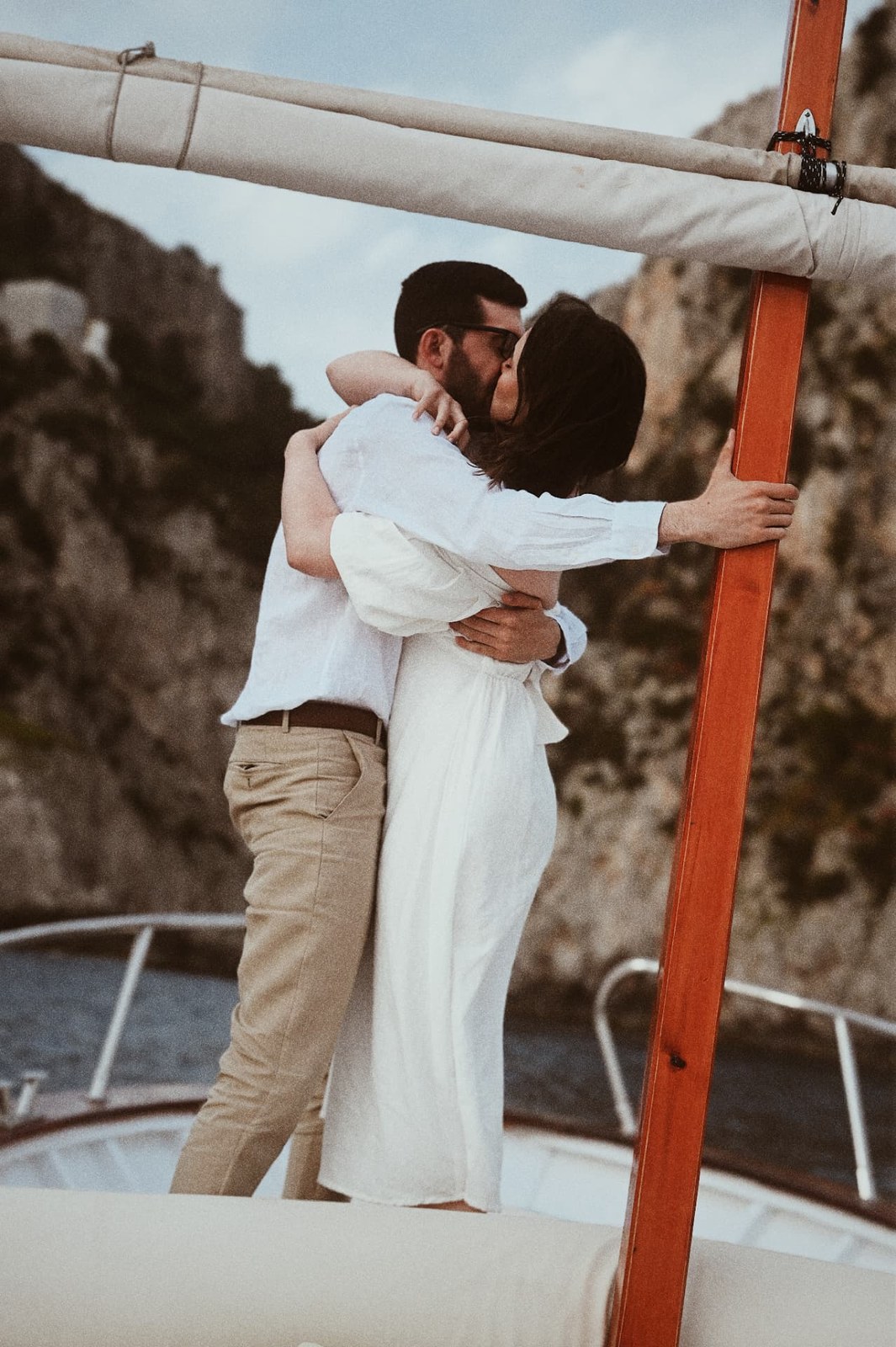 Couple kissing while holding the mast of a boat