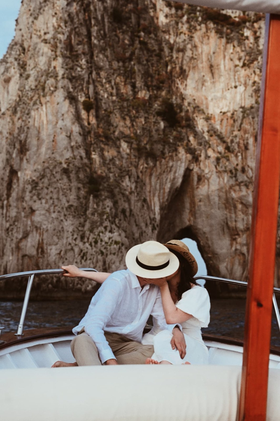 Couple in straw hats kissing beneath a limestone cliff